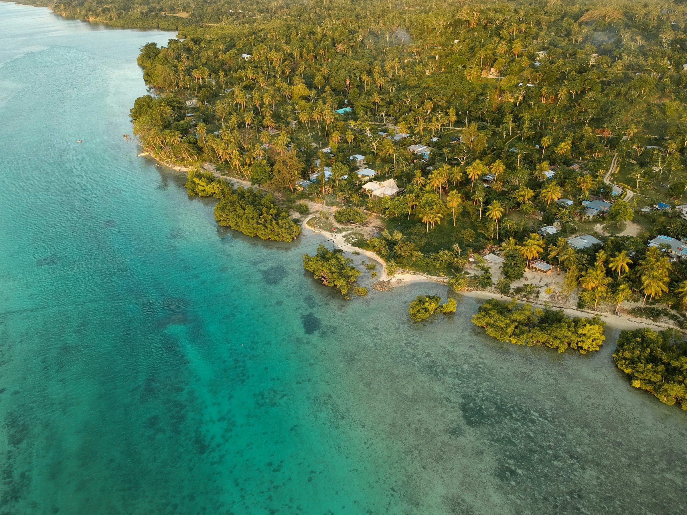 Aerial view of a village, mangroves and reef along the Vanuatu coast